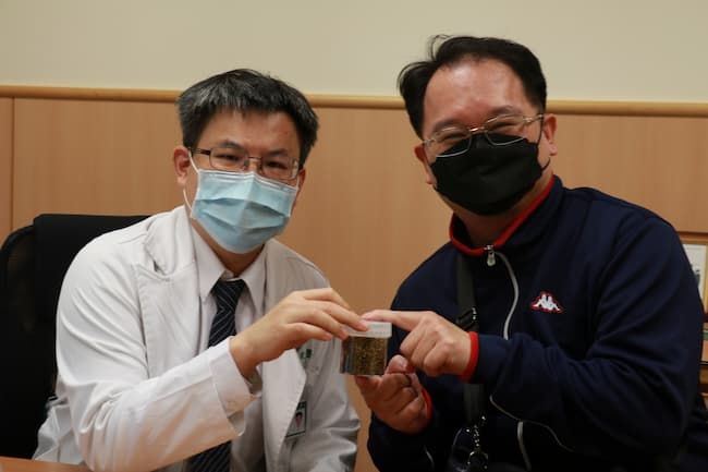 余政展主任(左)拿著膽囊取出的一整瓶膽結石,叮嚀回診病人清淡飲食保健康。